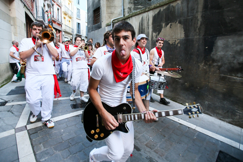 Imagen de un guitarrista tocando por la calle Jarauta mientras saca la lengua. PErtenece a una electrocharanga que va detrás y la guitarra es eléctrica