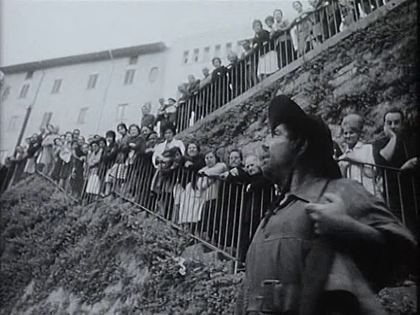 Se ve al actor que interpreta a Sancho Panza ataviado con ropa de campo y sombrero en primer plano, con unas doscientas personas dispuestas en la cuesta de Santo Domingo para ver el encierro